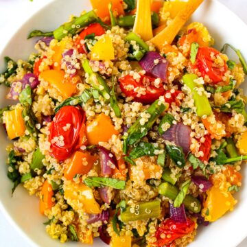 Overhead view of quinoa with roasted vegetables in a white serving bowl