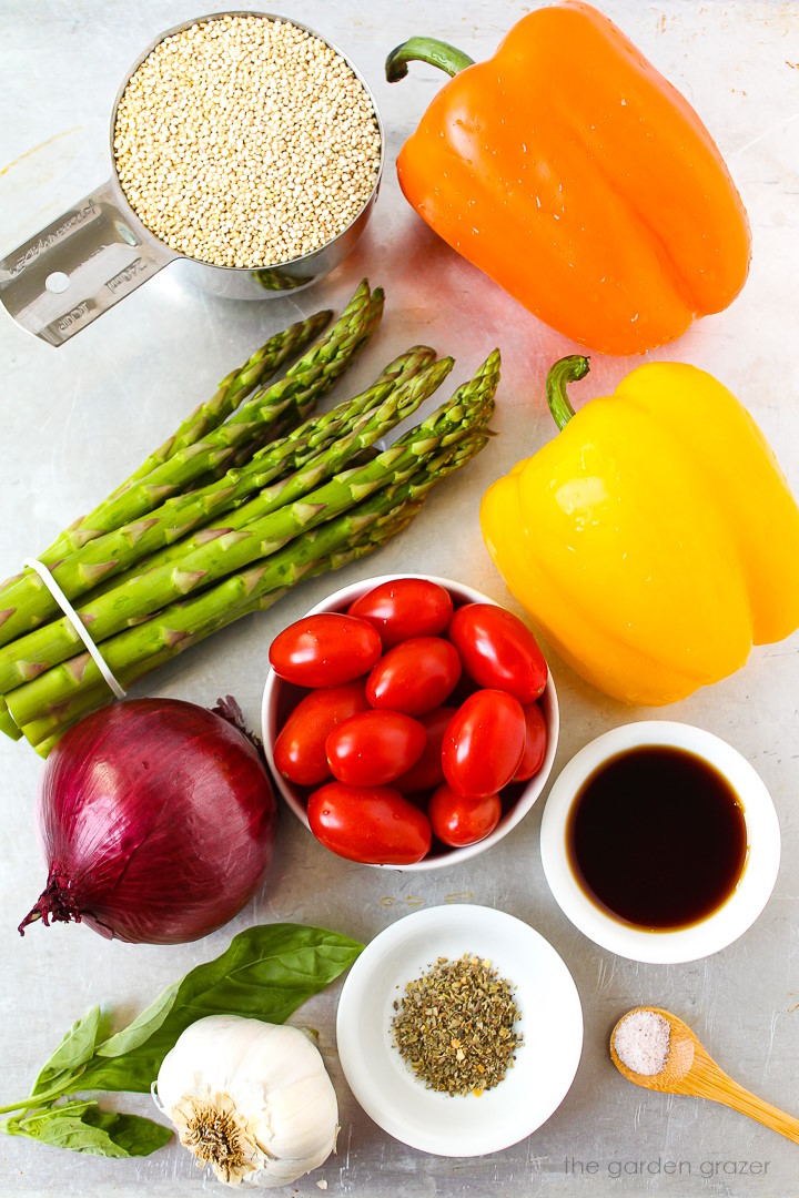 Bell peppers, asparagus, grape tomatoes, red onion, garlic, basil, and balsamic vinegar ingredients laid out on a metal tray