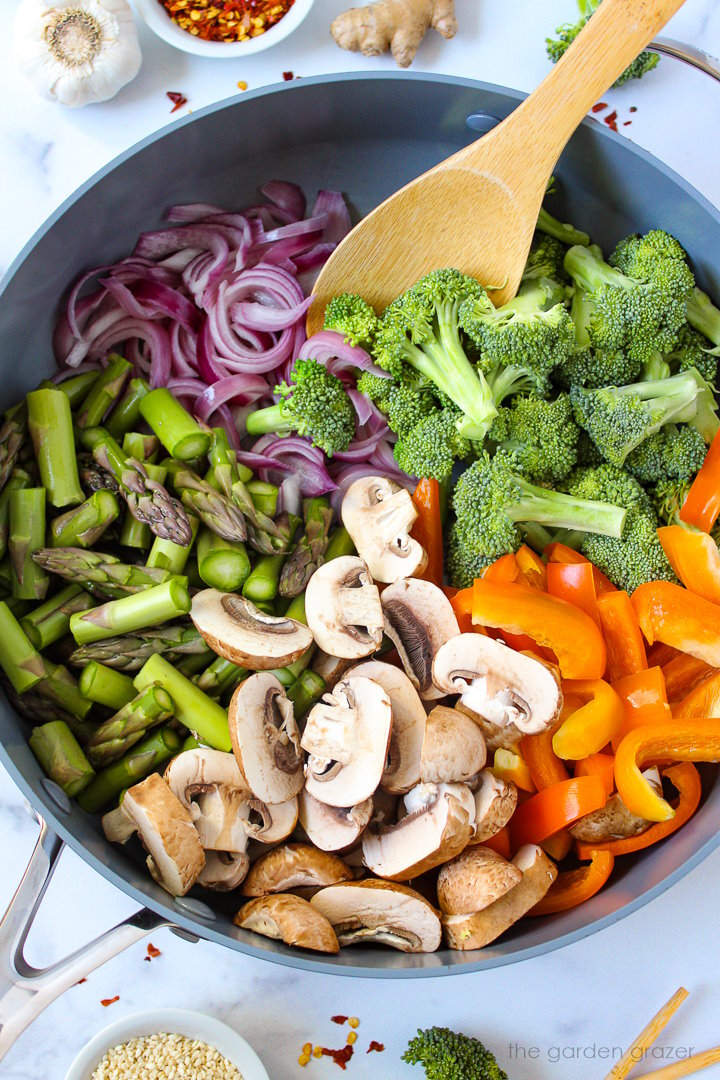 Overhead view of preparing stir fry vegetables in a large skillet before stirring together