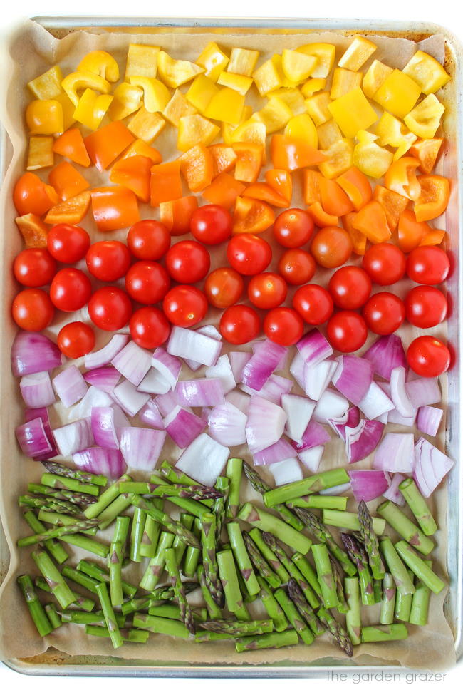 Sheet pan of chopped rainbow vegetables ready to roast