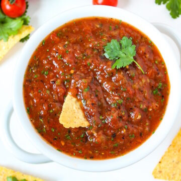 Restaurant style blender salsa served in a white bowl with chips and fresh cilantro