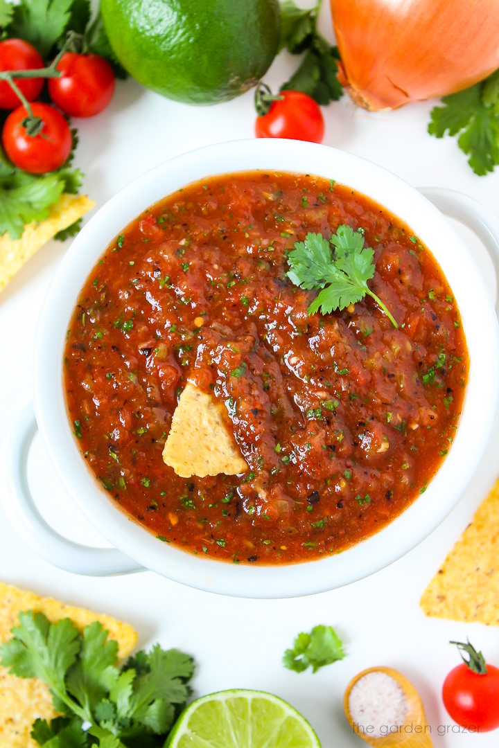 Restaurant style blender salsa served in a white bowl with chips and fresh cilantro