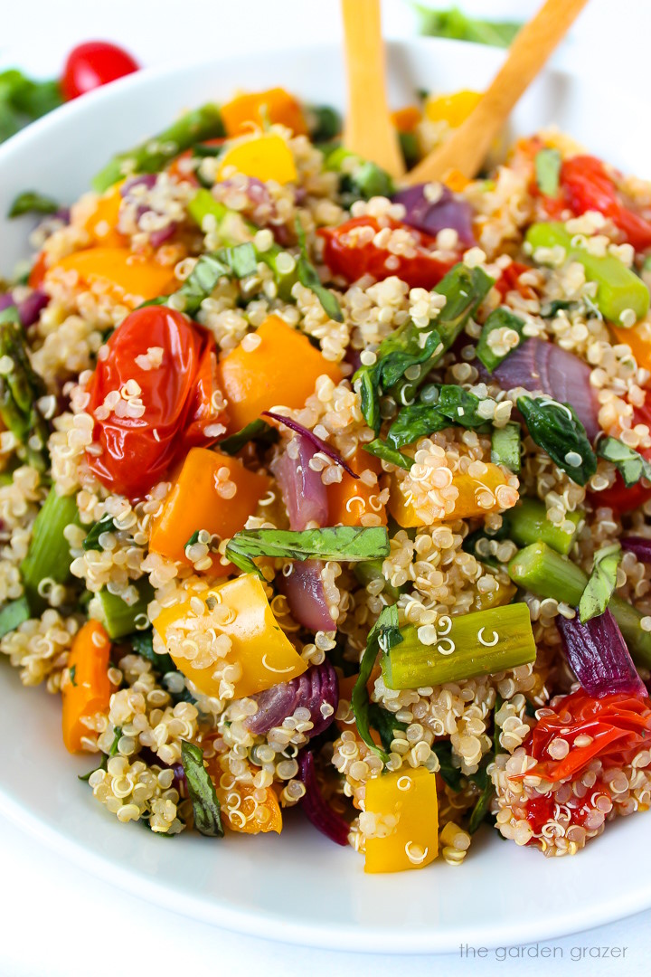 Close up view of quinoa with roasted vegetables on a white serving plate