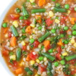 Bowl of vegan vegetable barley soup topped with parsley