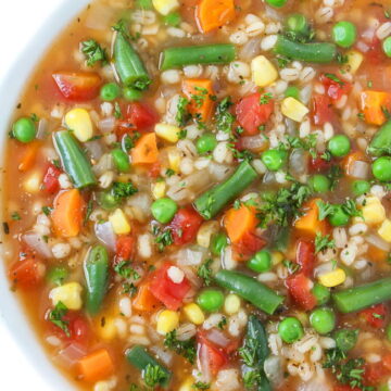 Bowl of vegan vegetable barley soup topped with parsley