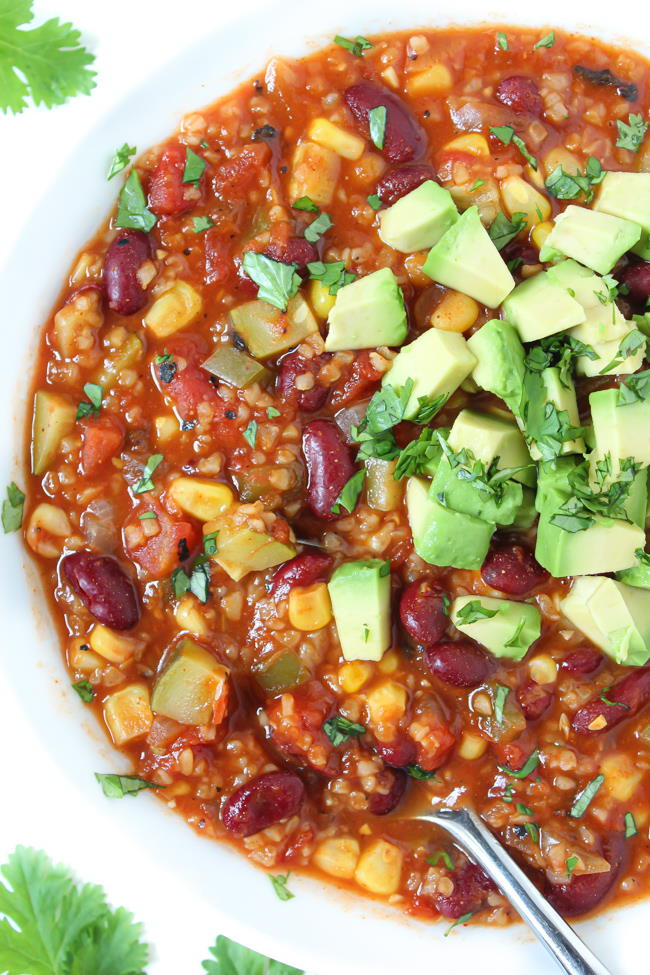 Vegan bulgur vegetable chili in a white bowl with avocado