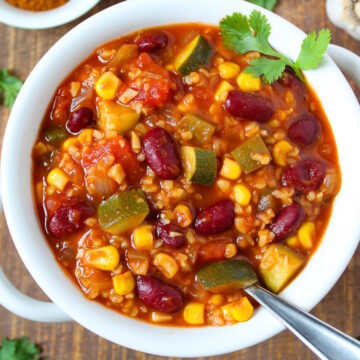 Vegan bulgur chili served in a white bowl with fresh cilantro on a wooden table