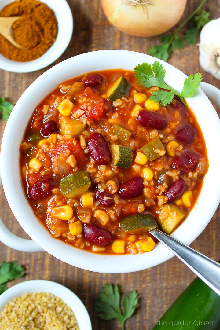 Vegan bulgur chili served in a white bowl with fresh cilantro on a wooden table