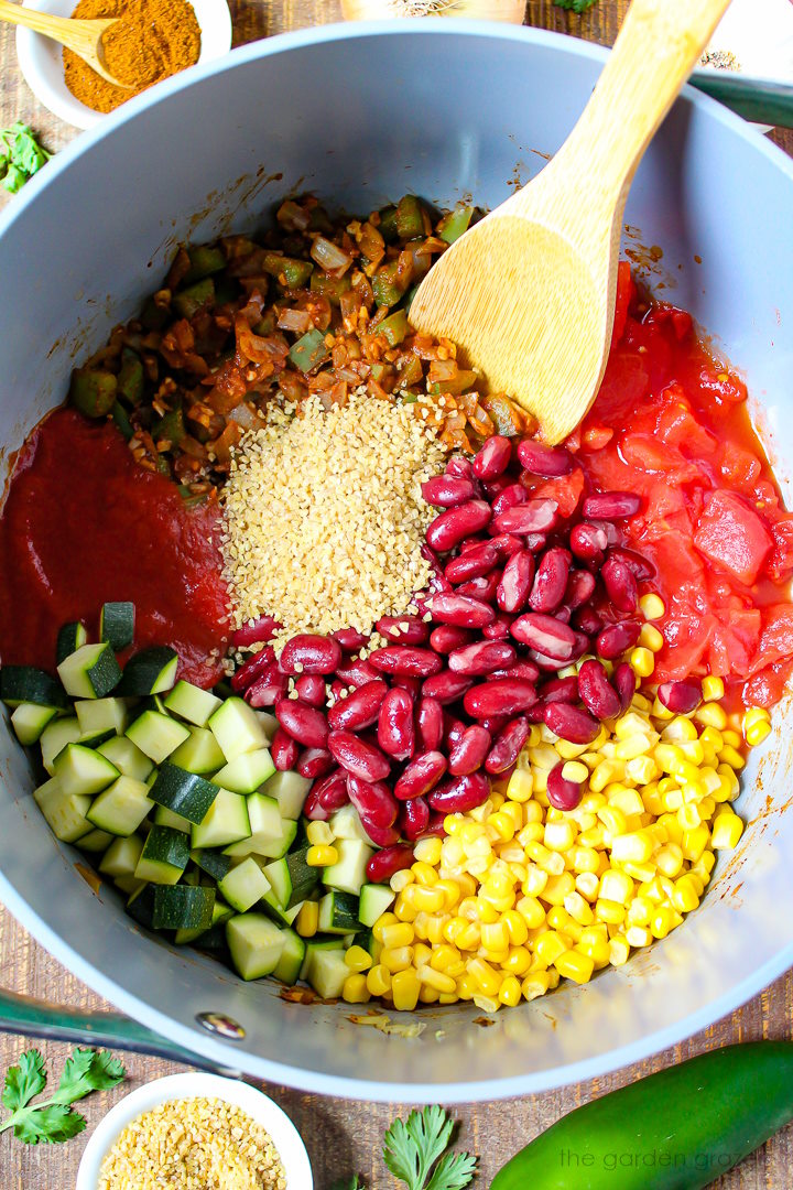 Overhead view of preparing bulgur vegetable chili ingredients in a large pot before stirring together