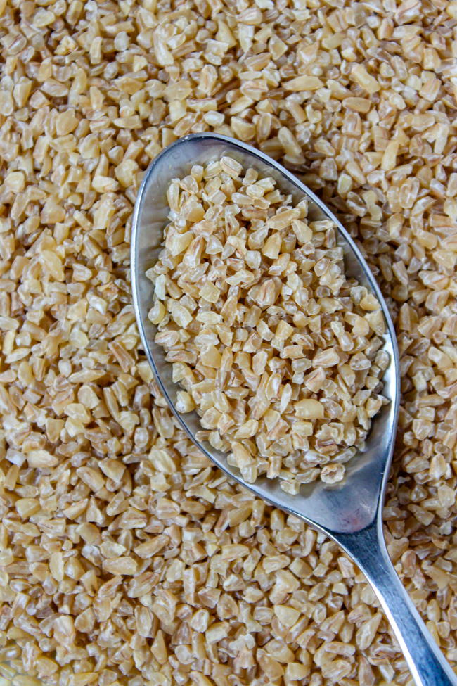 Close-up view of uncooked bulgur wheat on a plate with spoon