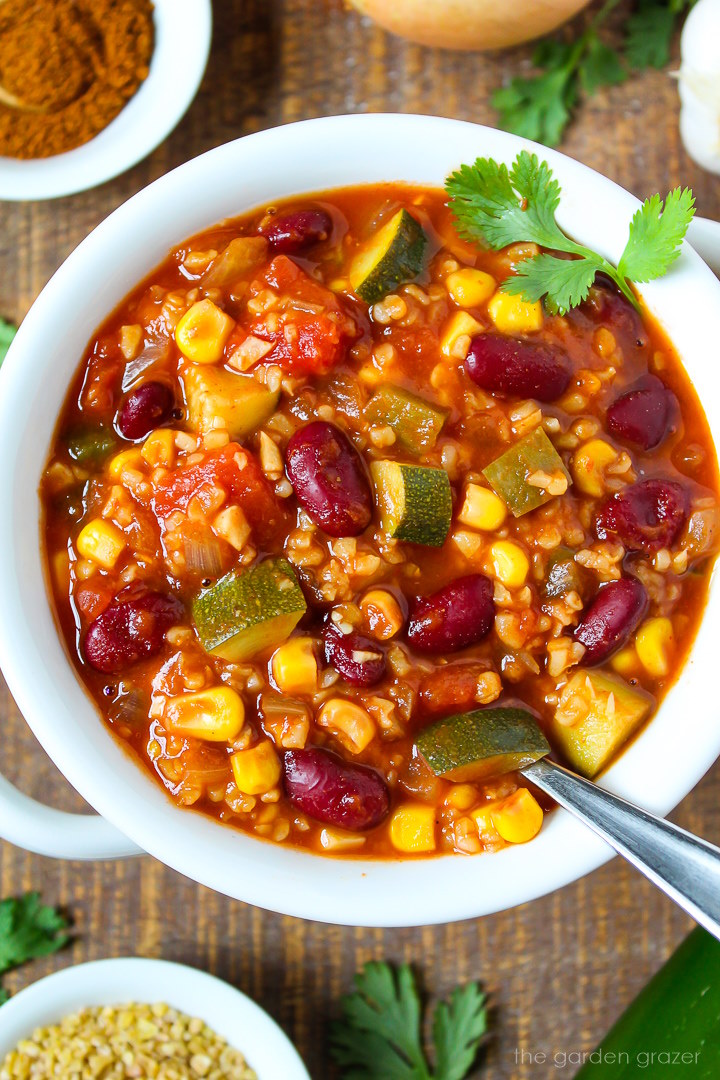 Close up view of bulgur vegetable chili in a white serving bowl on a wooden table
