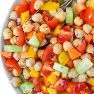 Vegan chickpea salad with vegetables in a bowl with spoon