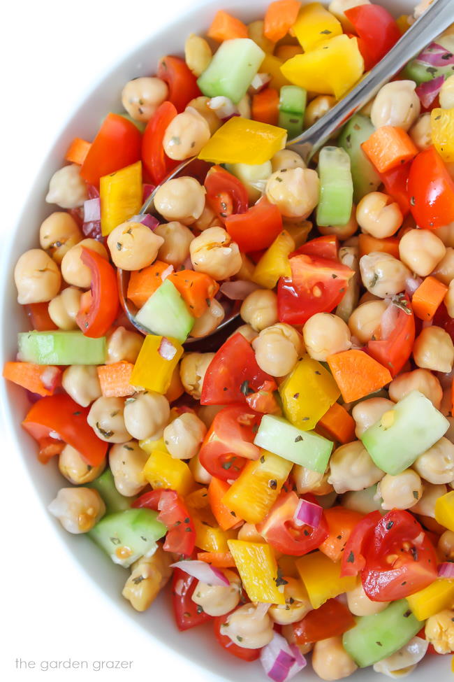 Vegan chickpea salad with vegetables in a bowl with spoon