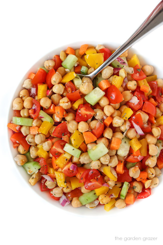 Garbanzo bean salad with lemon dressing in a white bowl with spoon