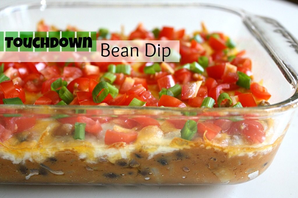 Vegan bean dip in a glass dish topped with tomatoes and green onions
