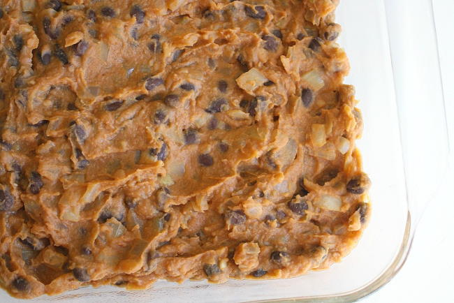 Preparing the bean dip in a glass dish