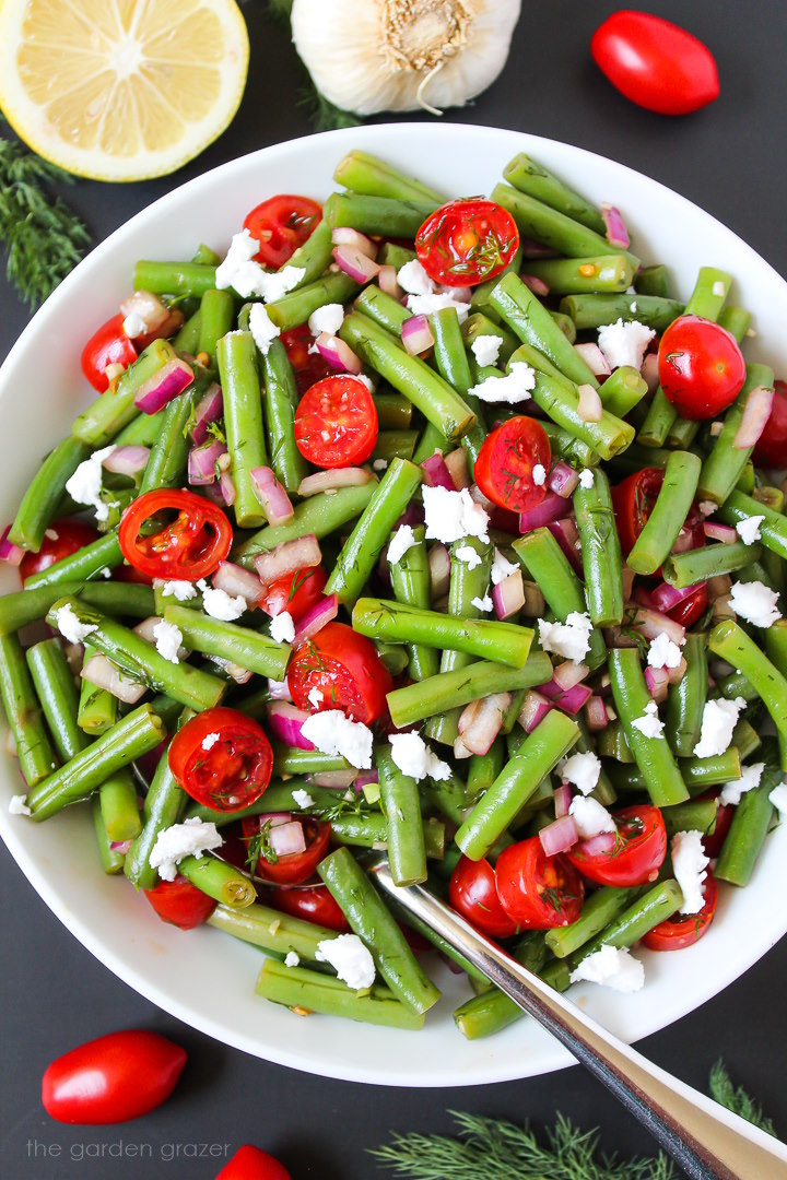 Balsamic green beans salad on a white plate with serving spoon
