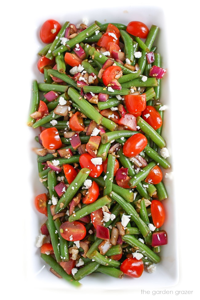 Vegan green bean salad with tomato and balsamic on a long white plate