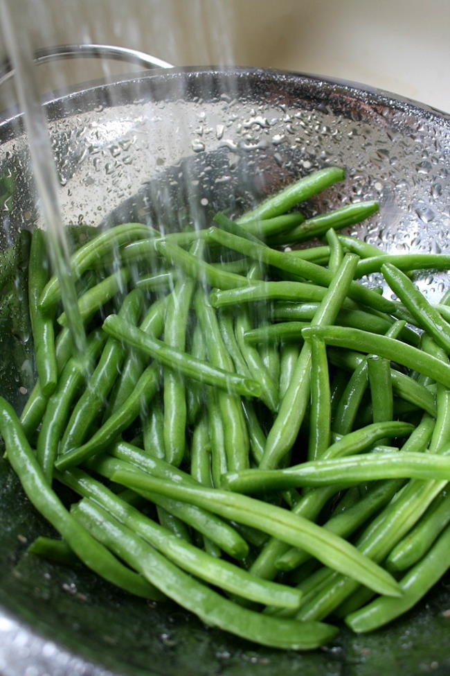 Fresh green beans being rinsed in a colander