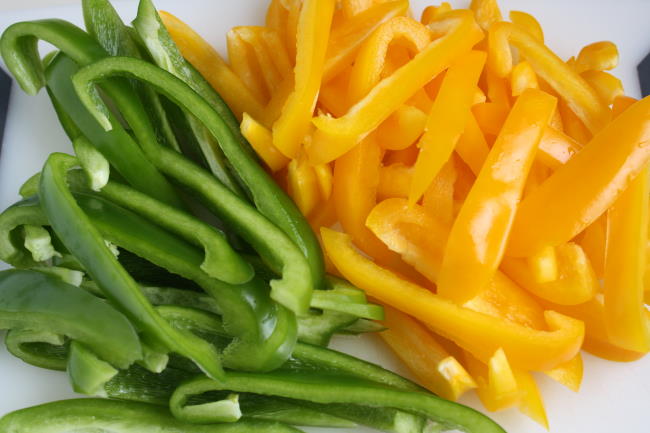 Sliced yellow and green bell peppers on a cutting board