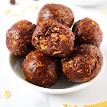 Chocolate oat balls with peanut butter stacked together in a white serving bowl