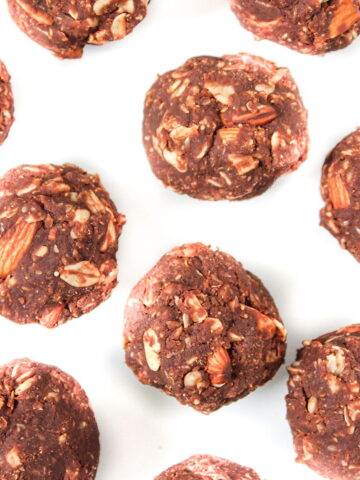 Chocolate oat balls spaced apart on a white table