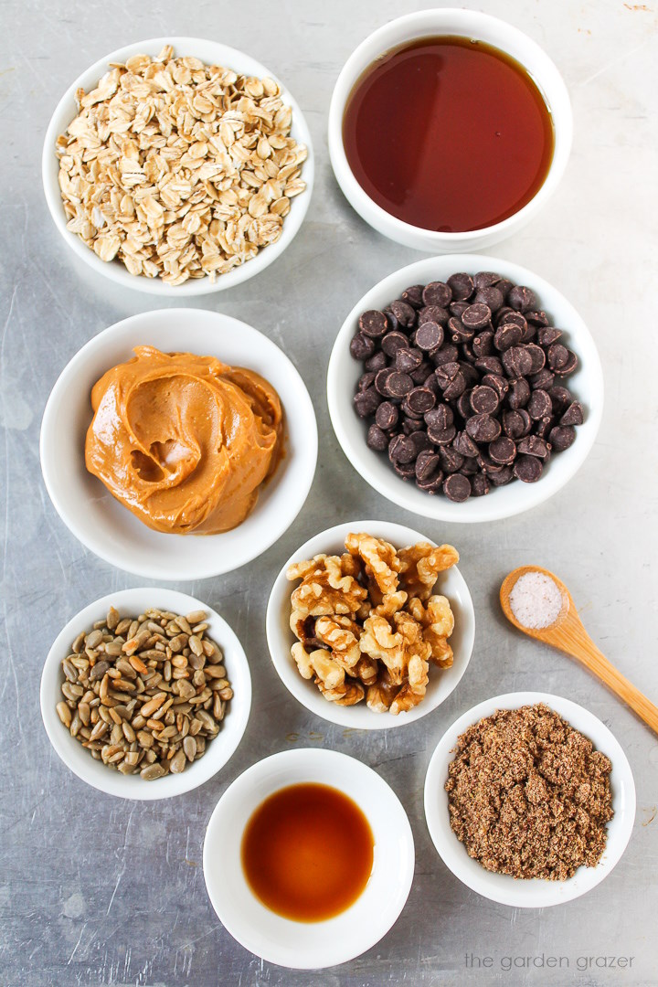 Maple syrup, chocolate chips, peanut butter, walnuts, flax seed, and vanilla ingredients laid out on a metal tray