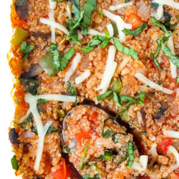 Close up view of vegan pizza quinoa casserole in a glass baking dish with serving spoon