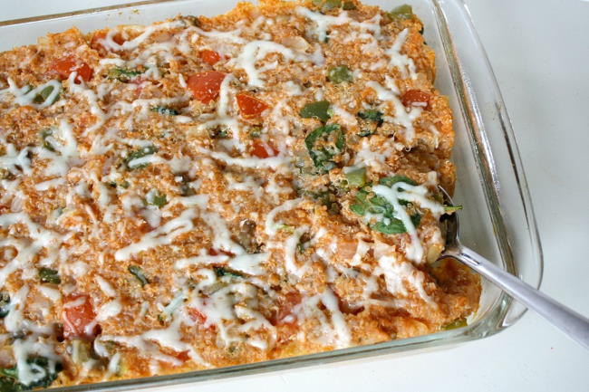 Vegan pizza quinoa casserole in a large glass baking dish with spoon