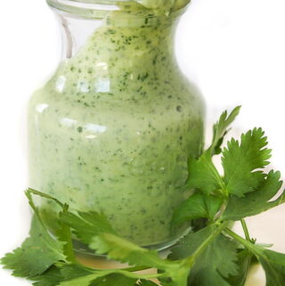 Jar of creamy cilantro-lime dressing with fresh cilantro in front