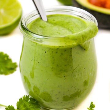 Vegan creamy cilantro lime dressing in a small glass jar with serving spoon