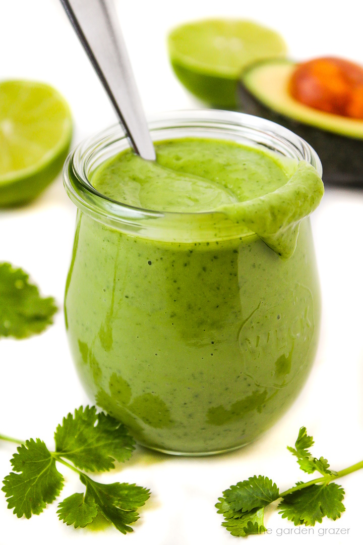 Vegan creamy cilantro lime dressing in a small glass jar with serving spoon