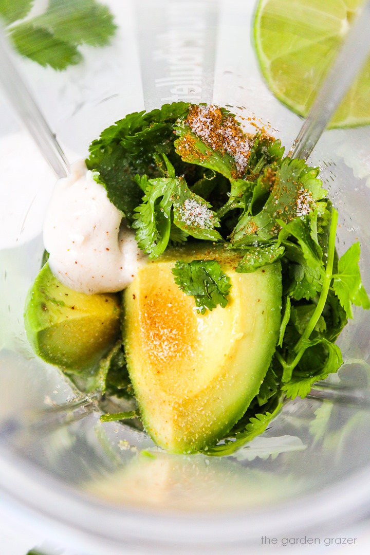 Overhead view of preparing vegan creamy cilantro lime dressing in a small blender cup before mixing together