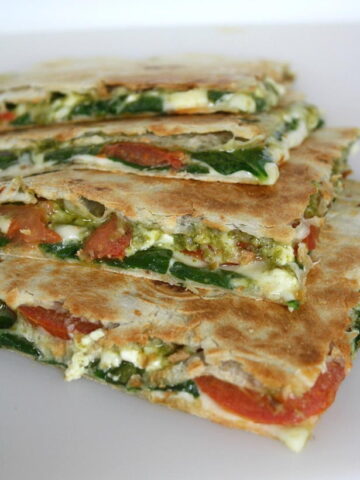 Vegan pesto quesadillas with tomato and spinach cut in half