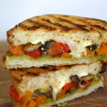 Vegan vegetable pesto panini cut in half on a cutting board