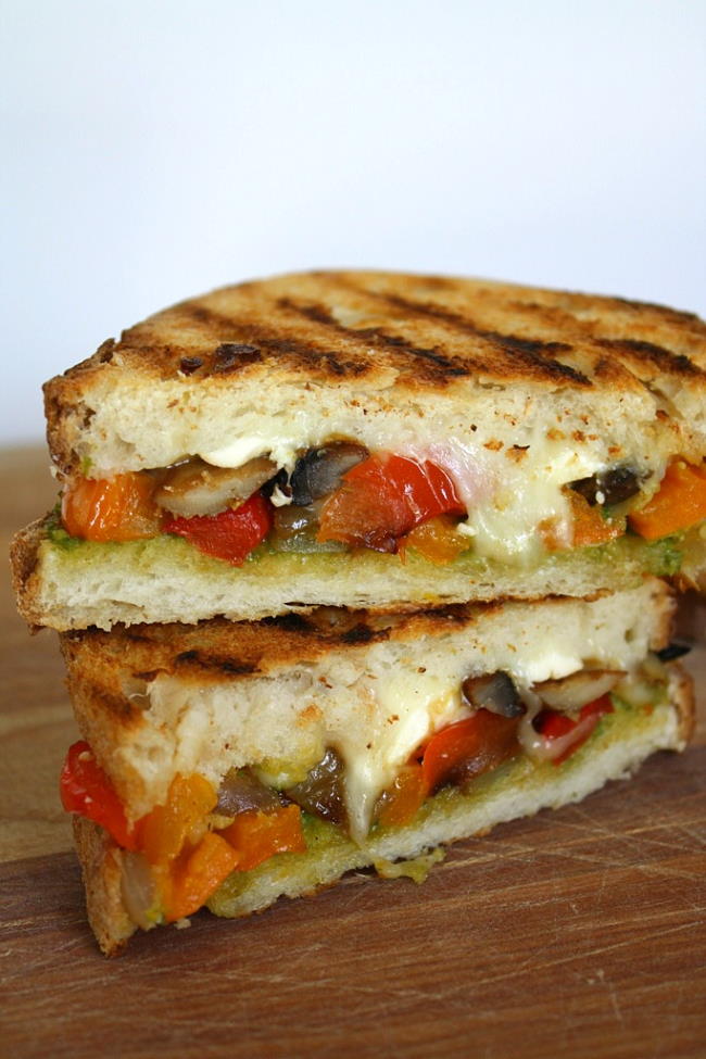 Vegan vegetable pesto panini cut in half on a cutting board