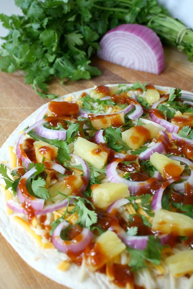 Open-faced BBQ quesadilla on a cutting board with cilantro and onion