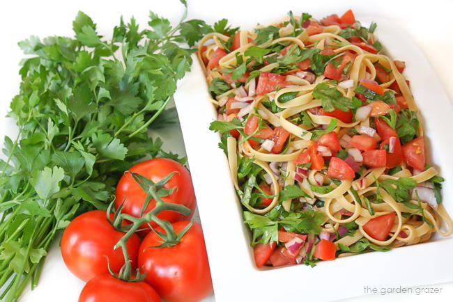 Vegan tomato fettuccine pasta in a white bowl with parsley