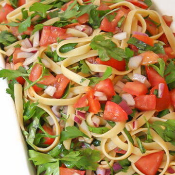 Fresh tomato pasta in a bowl with basil and parsley