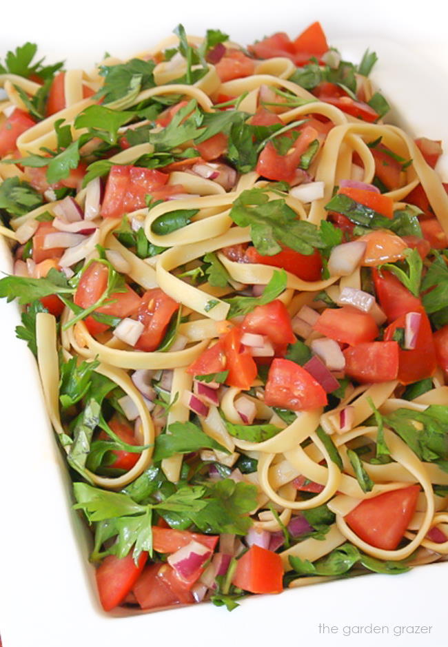 Fresh tomato pasta in a bowl with basil and parsley