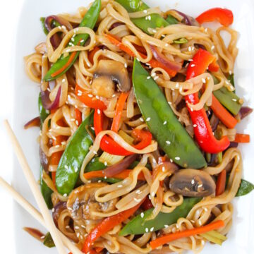 Overhead view of vegan vegetable lo mein on a white plate with chopsticks