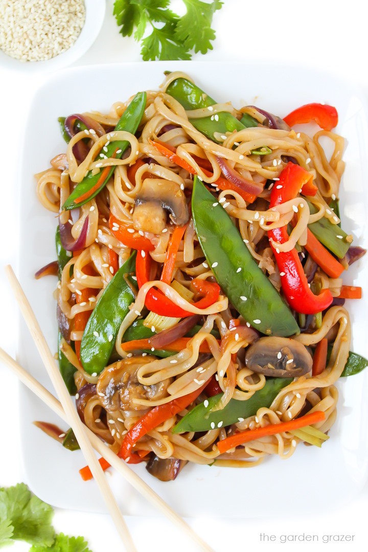 Overhead view of vegan vegetable lo mein on a white plate with chopsticks