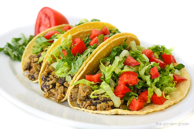 Plate of three black bean lentil tacos with lettuce and tomato