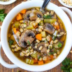 Mushroom barley soup served in a white bowl on a wooden table