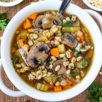 Mushroom barley soup served in a white bowl on a wooden table
