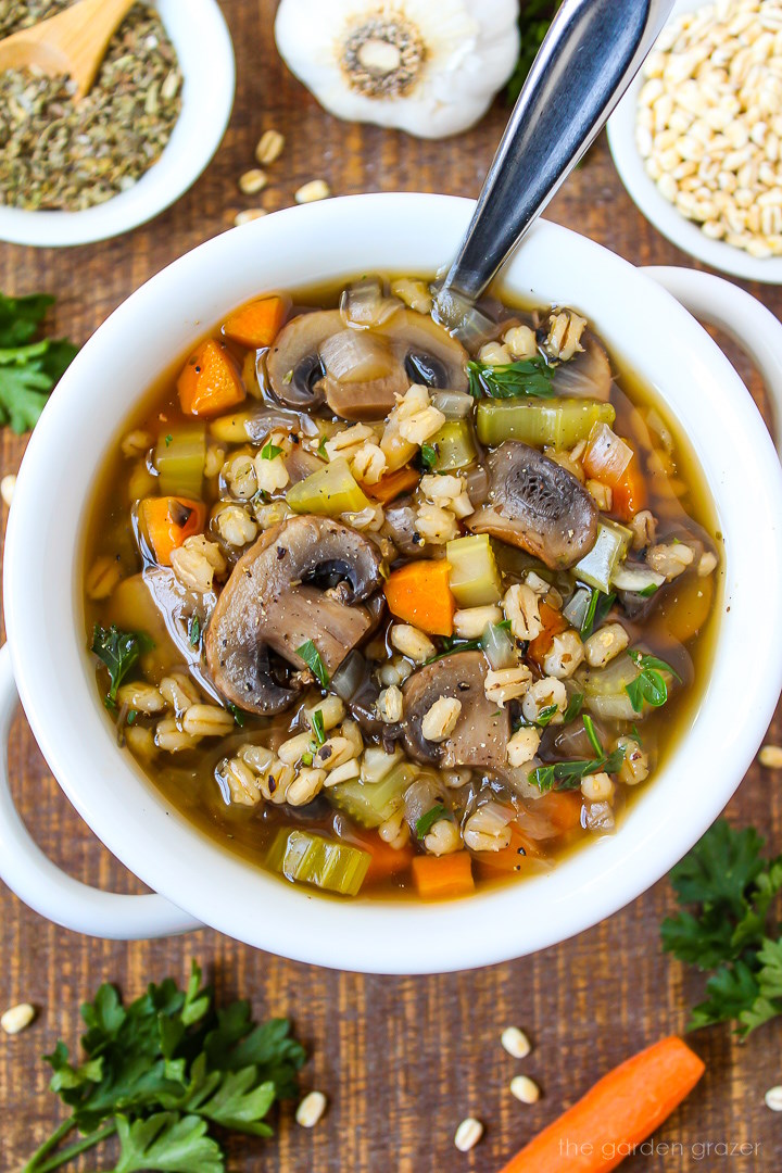 Mushroom barley soup served in a white bowl on a wooden table