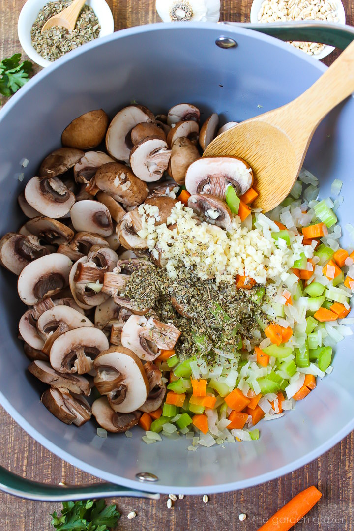 Overhead view of preparing soup ingredients in a large stockpot with wooden spoon