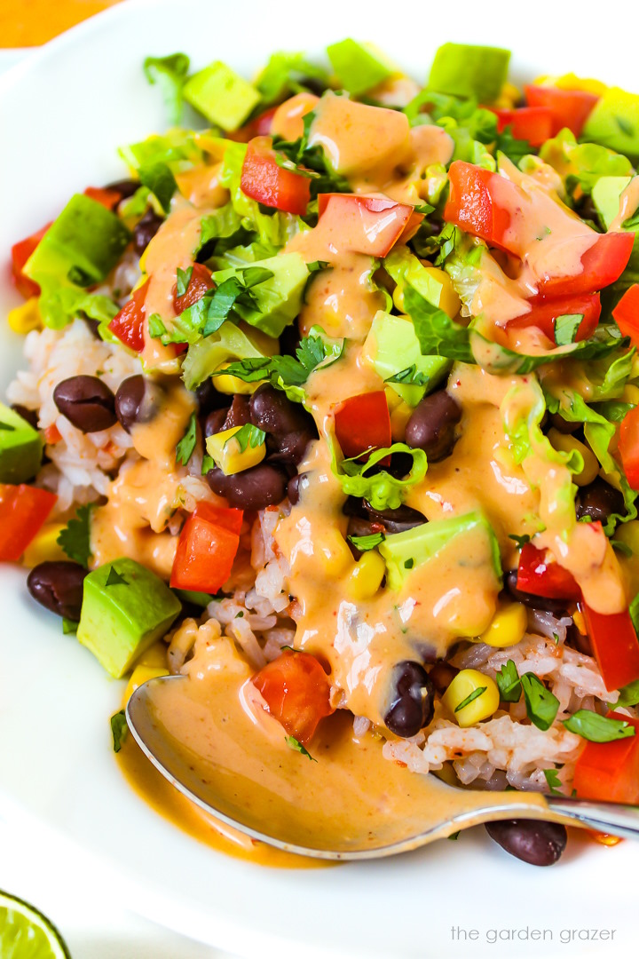 Close up view of vegan black bean burrito bowl with chipotle sauce on a white plate
