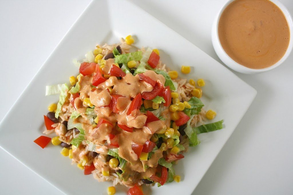overhead view of burrito bowl on a plate with chipotle dressing on the side