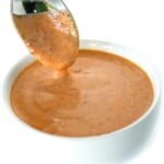 Spoon dipping into a small bowl of creamy chipotle sauce